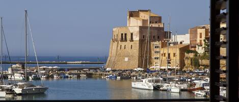 A harbor with boats and a historic building with a tower.