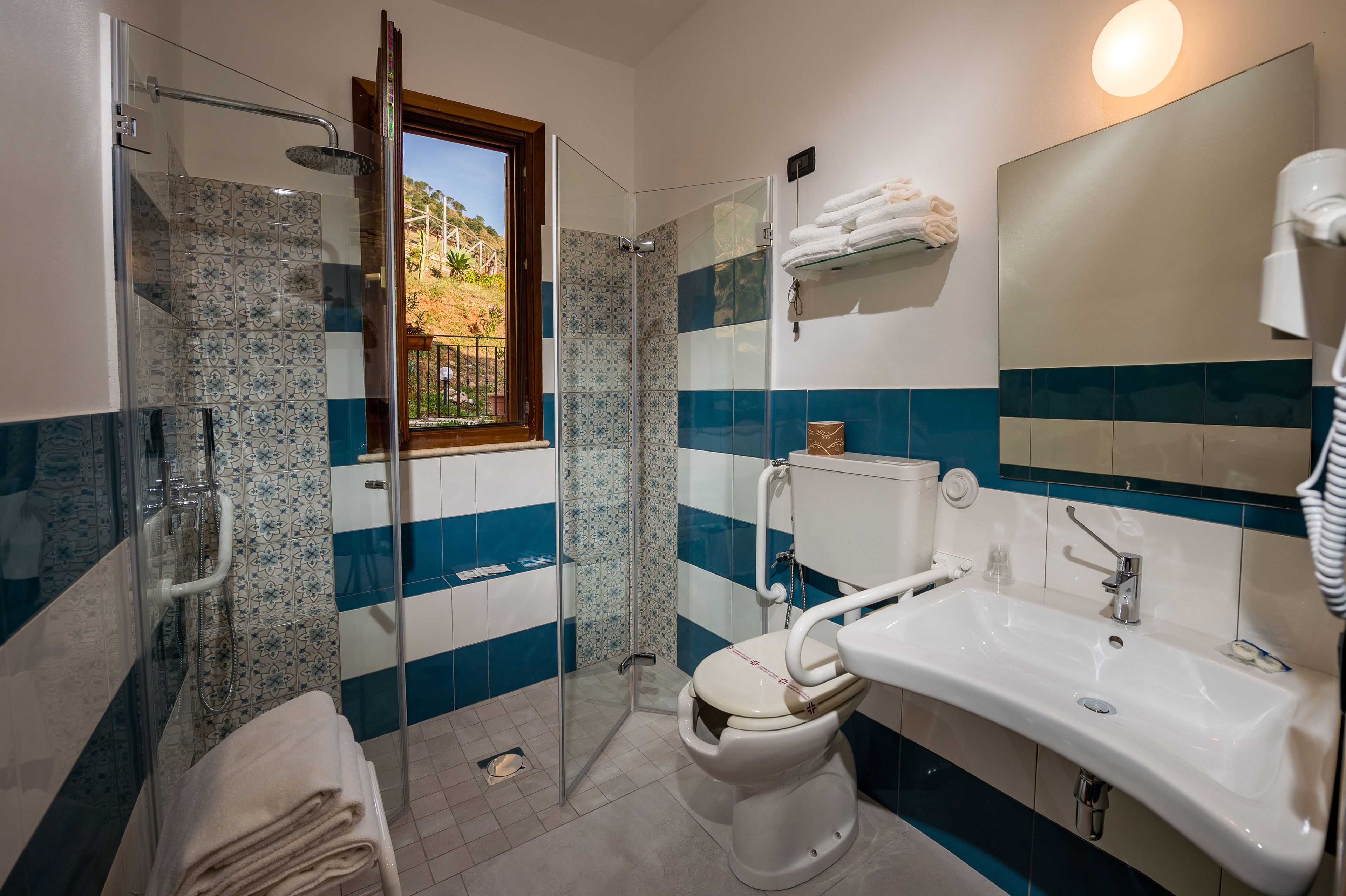 A bathroom with a glass-enclosed shower, a toilet, a sink, and a mirror.