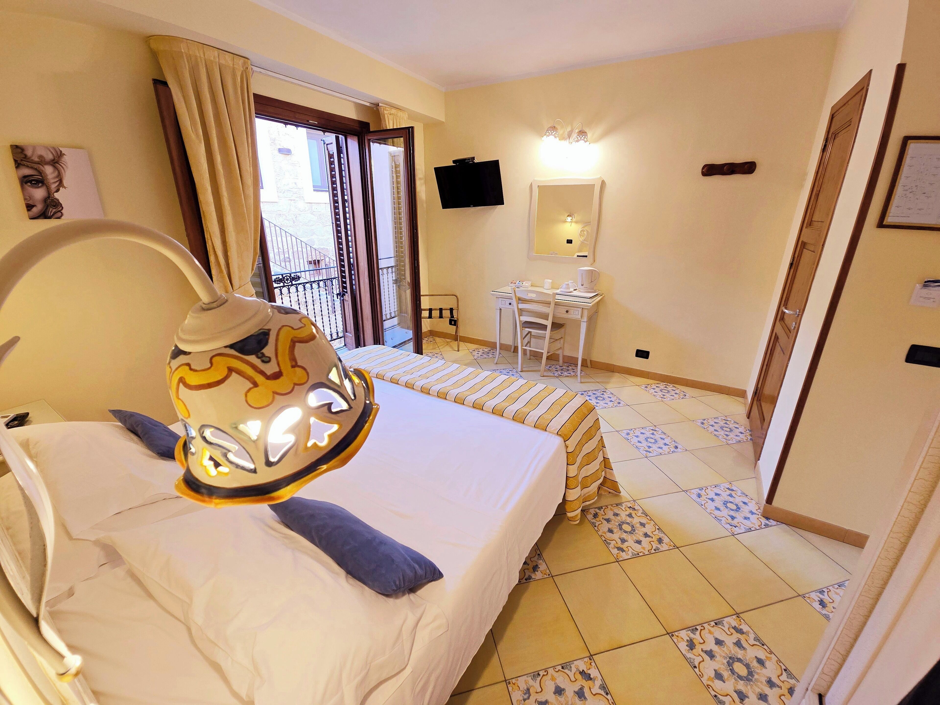 Ein Hotelzimmer mit Bett, Schreibtisch, Stuhl, Fernseher und einem Balkon.