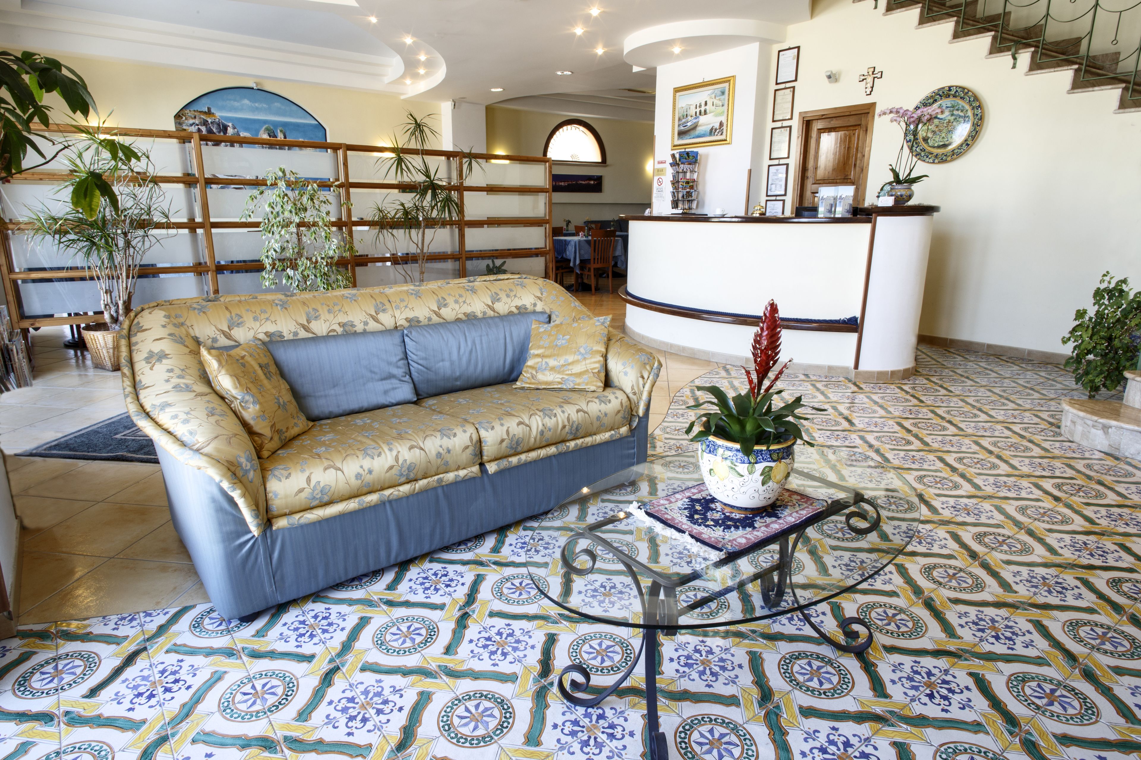 A spacious lobby with a sofa, a reception desk, and a patterned floor.