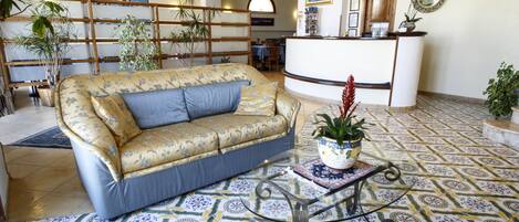 A spacious lobby with a sofa, a reception desk, and a patterned floor.