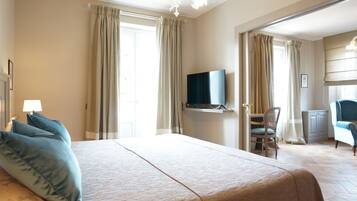 Une chambre d’hôtel avec un grand lit, un téléviseur posé sur un meuble, un bureau avec une chaise et une armoire.