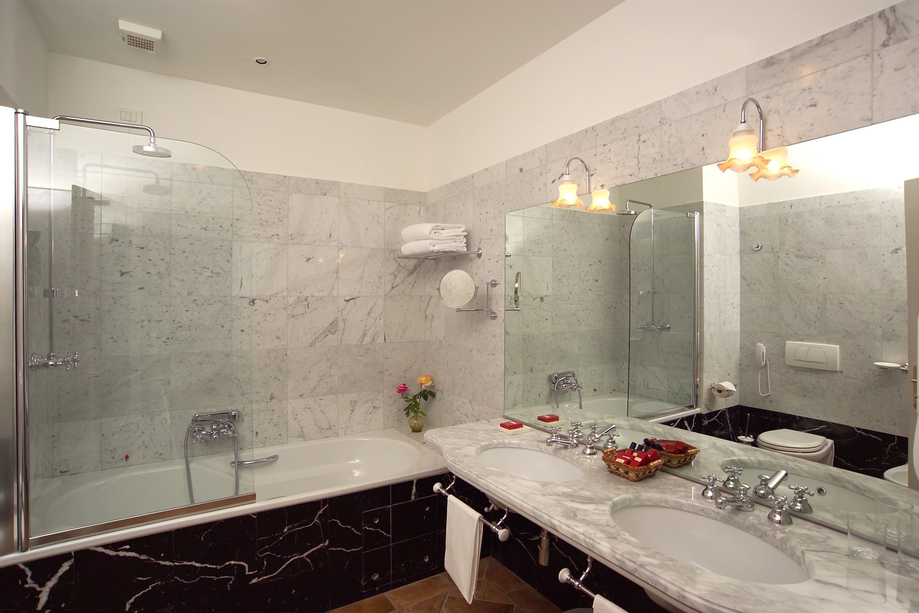 A modern bathroom with two sinks, a glass shower enclosure, and a large mirror.