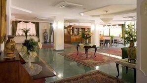 Un hall d’entrée spacieux, doté d’un sol ciré, d’un comptoir de réception et d’un espace détente avec une table et des chaises.