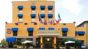 Un hôtel à la façade jaune, orné de nombreux drapeaux et doté d’une terrasse.