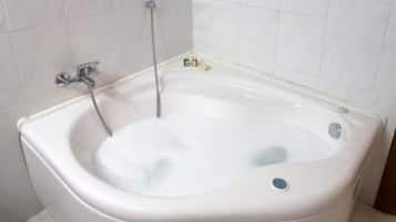 Uma banheira de canto com chuveiro manual e torneira.