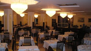 Un restaurant doté de nombreuses tables et chaises, chacune étant mise avec des verres à vin et des couverts.