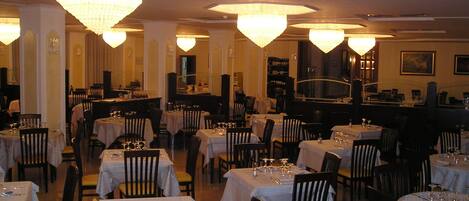A restaurant with multiple tables and chairs, each set with wine glasses and cutlery.