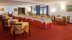 A dining area with tables set for a meal, chairs, and a long table with a red tablecloth.