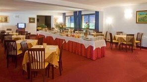 A dining area with tables set for a meal, chairs, and a long table with a red tablecloth. - Valdenza (Campegine)