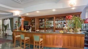 Un espace bar avec un comptoir en bois, des tabourets de bar et des étagères remplies de bouteilles.