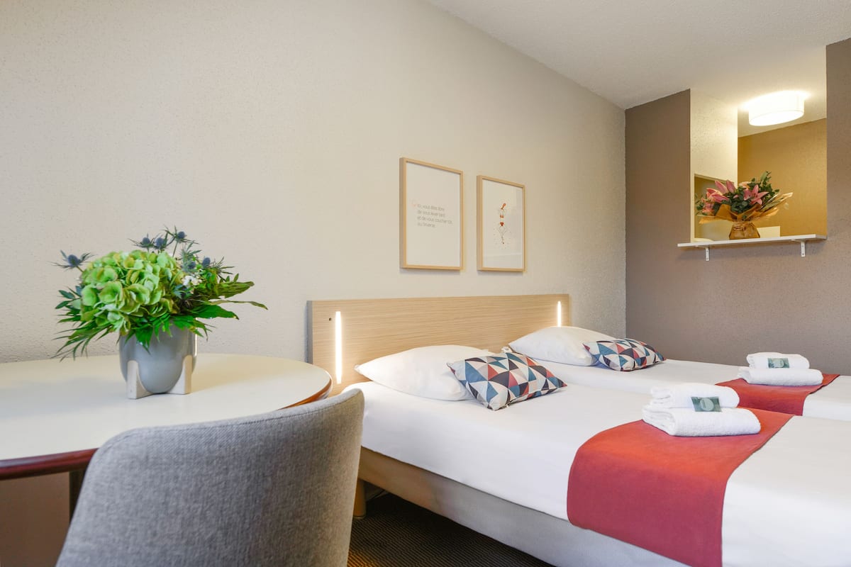 Una habitación de hotel con cama, una silla, una mesa y una planta en maceta.