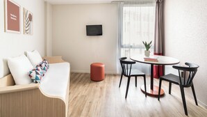 Una sala de estar moderna con un sofá, un reposapiés y una zona de comedor con sillas y una mesa.