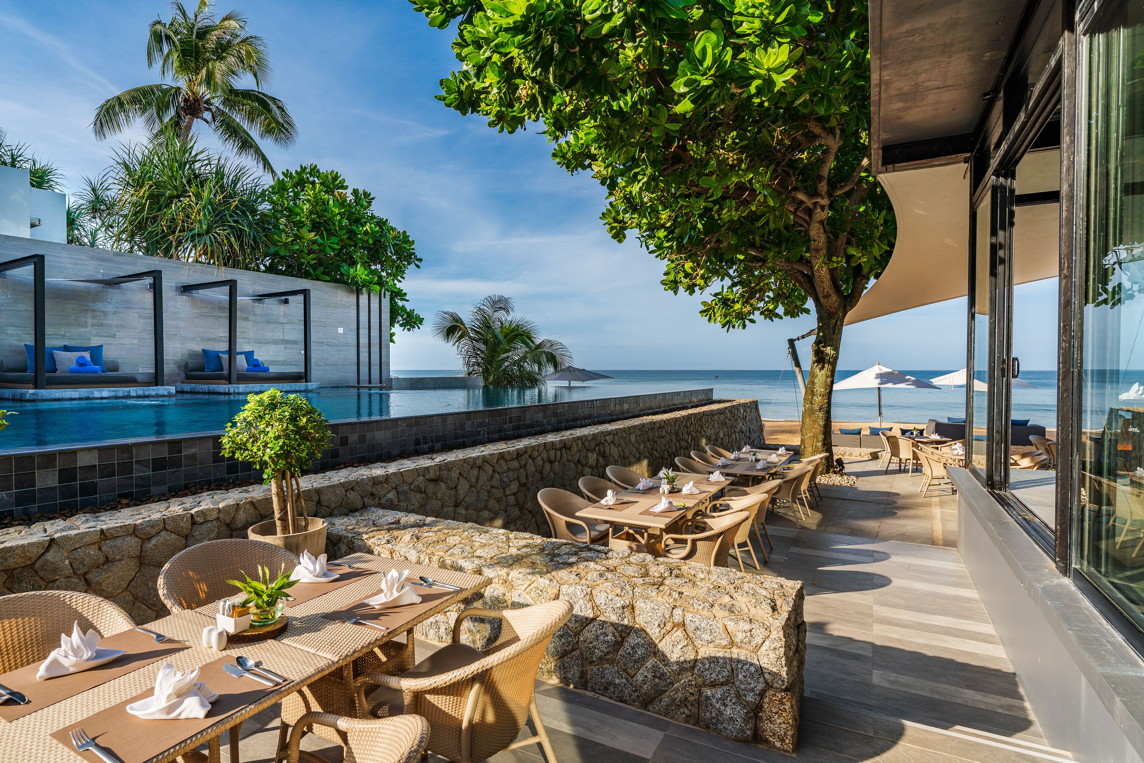 A poolside area with outdoor seating and a view of the ocean.
