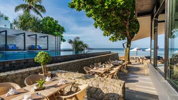 A poolside area with outdoor seating and a view of the ocean.