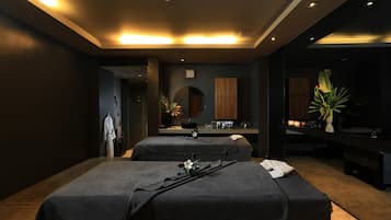 Experience a serene spa retreat with two massage tables, a large mirror, and a potted plant.