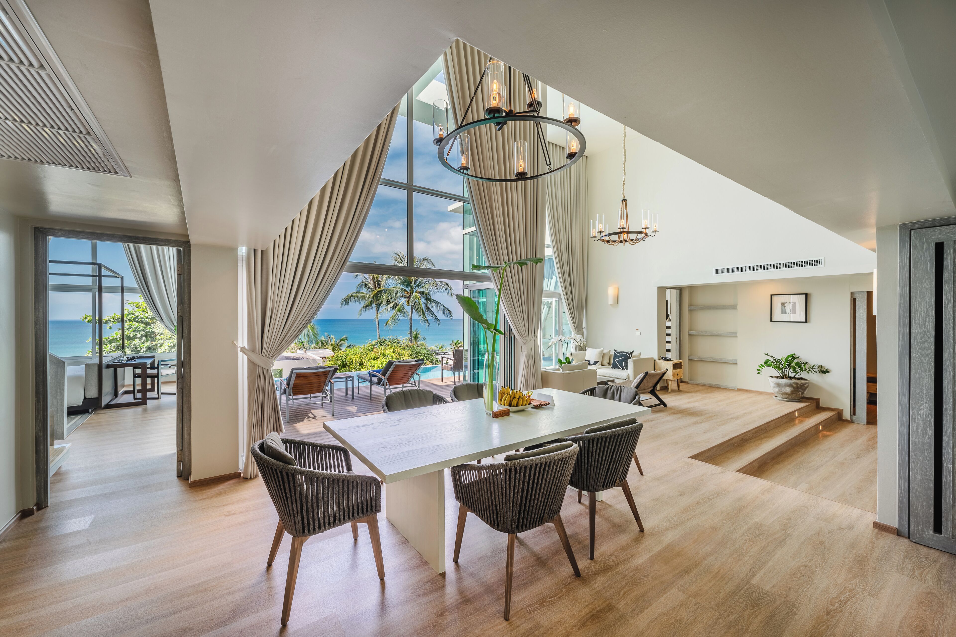 A spacious dining area with a large table and chairs, a view of the ocean, and a modern interior design.