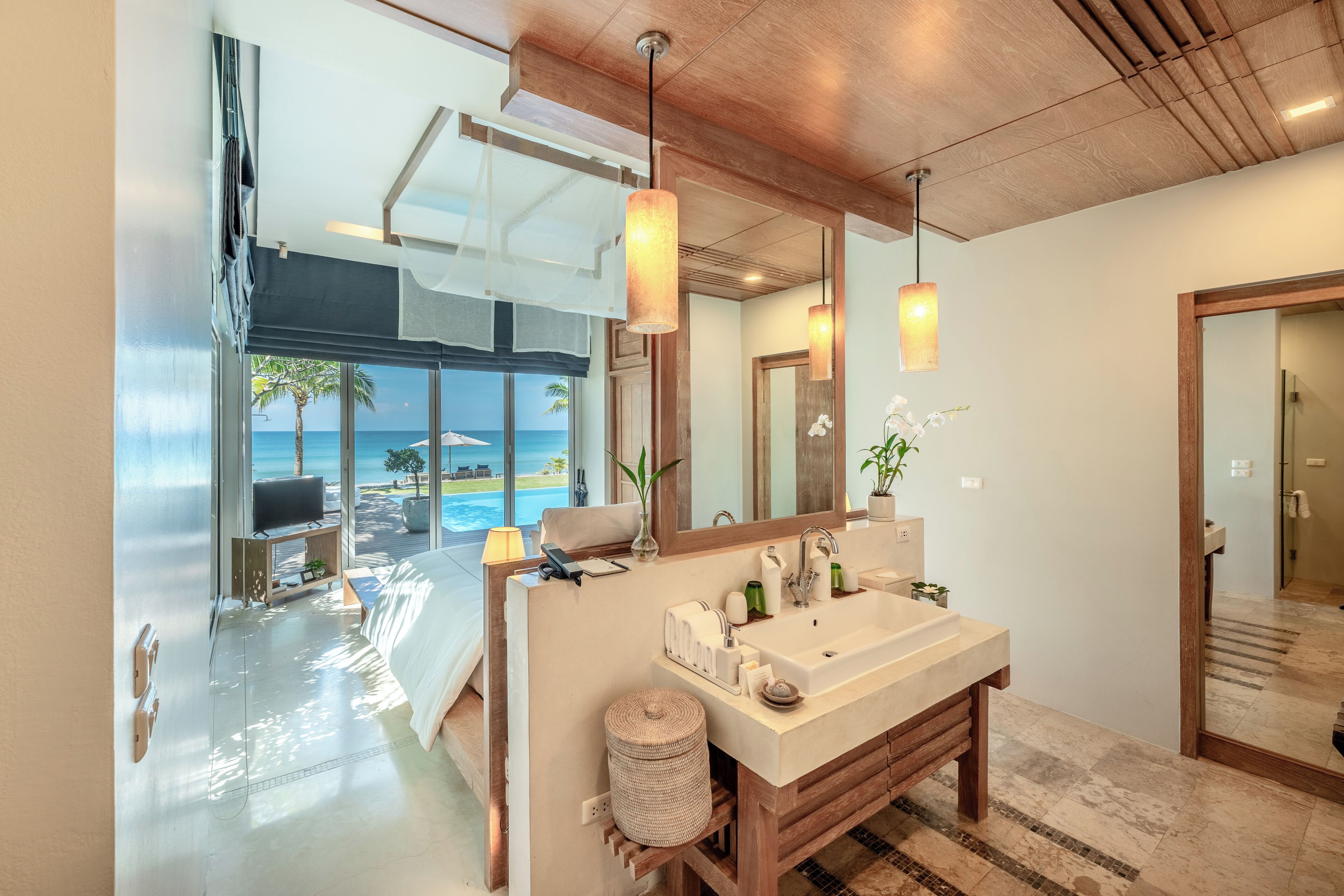 A modern bathroom with a large mirror, wooden vanity, and a view of the ocean.