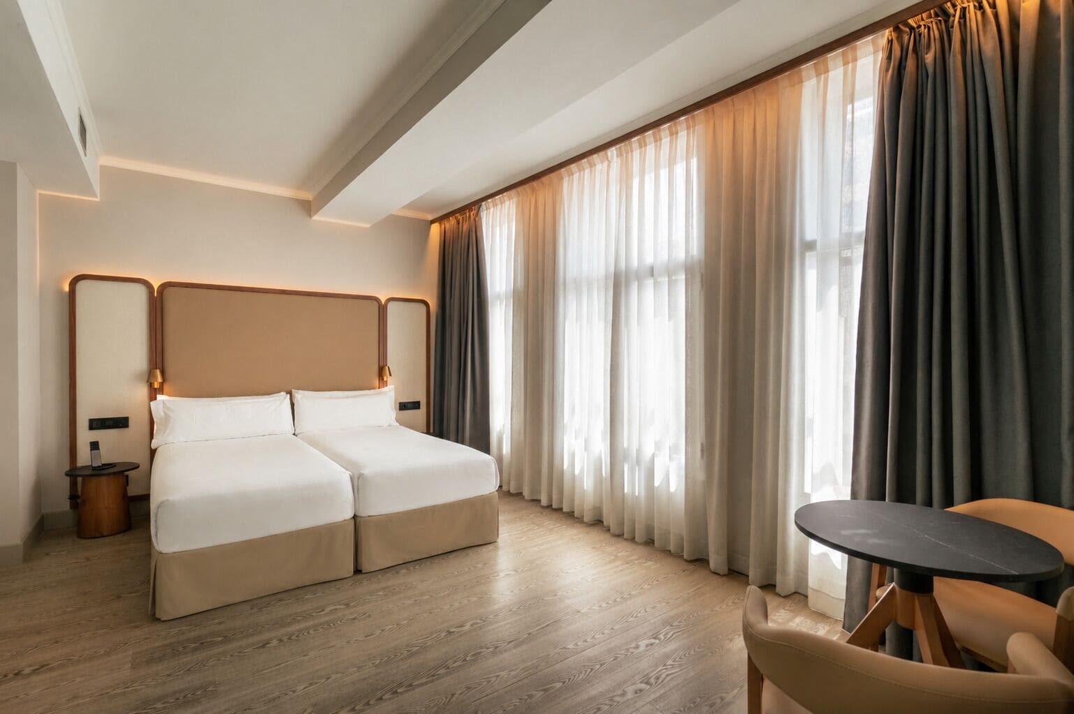 Una habitación de hotel con cama doble, una mesita pequeña y una silla.