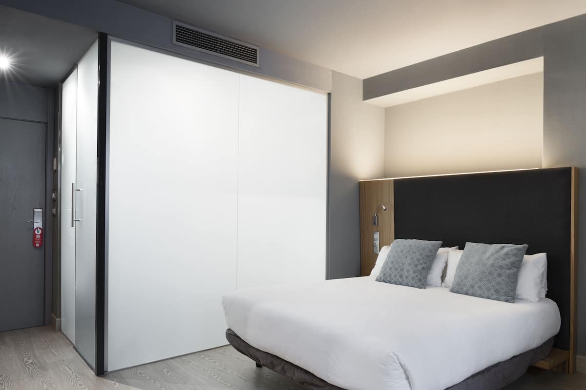 Un dormitorio moderno con cama, armario y mesita de noche.