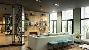Una sala de estar moderna con un sofá verde claro, una chimenea y una estantería llena de libros y objetos decorativos.