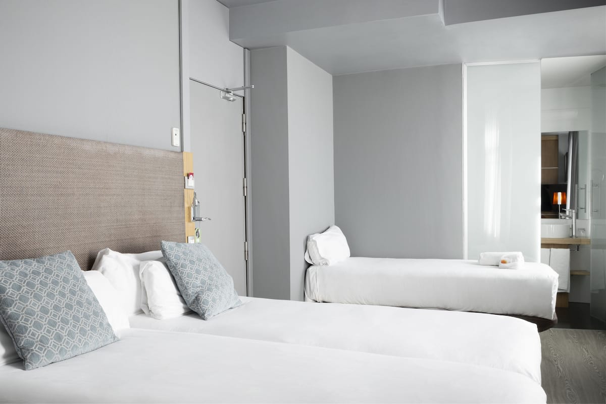 Una habitación de hotel moderna con dos camas, un espejo grande y un cabecero de madera.