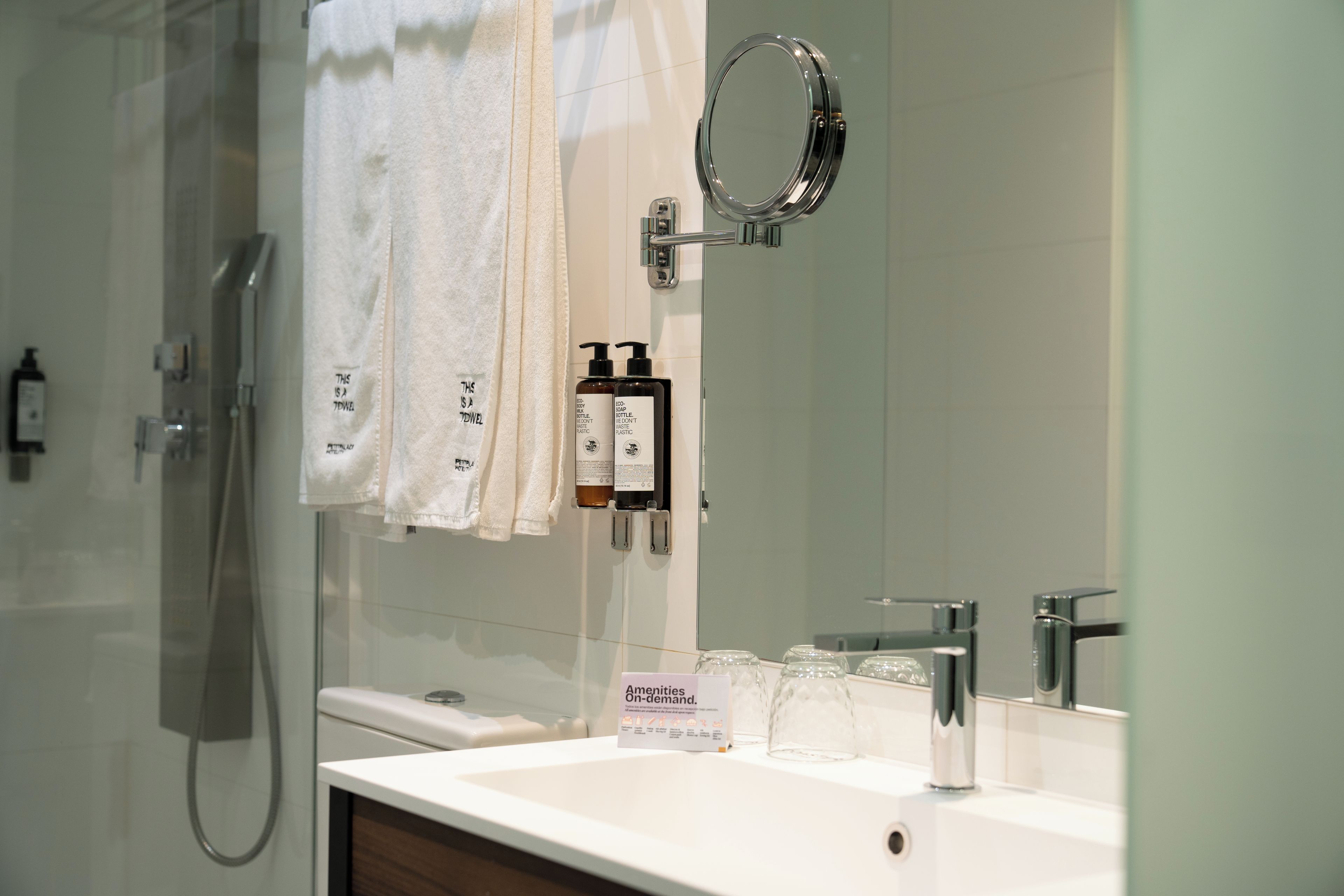 Un baño con ducha, lavamanos, espejo y artículos de aseo.