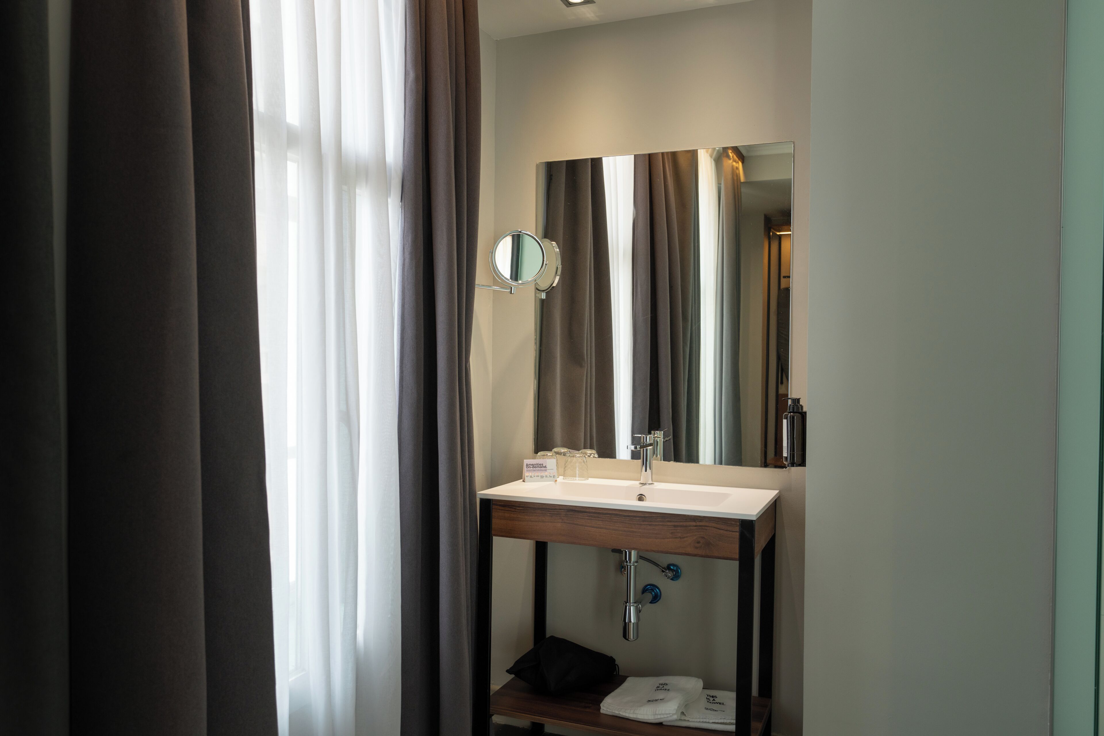 Un bagno d'albergo con lavandino, specchio e portasciugamani.