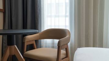 A hotel room with a single chair, a small table, and a bed.