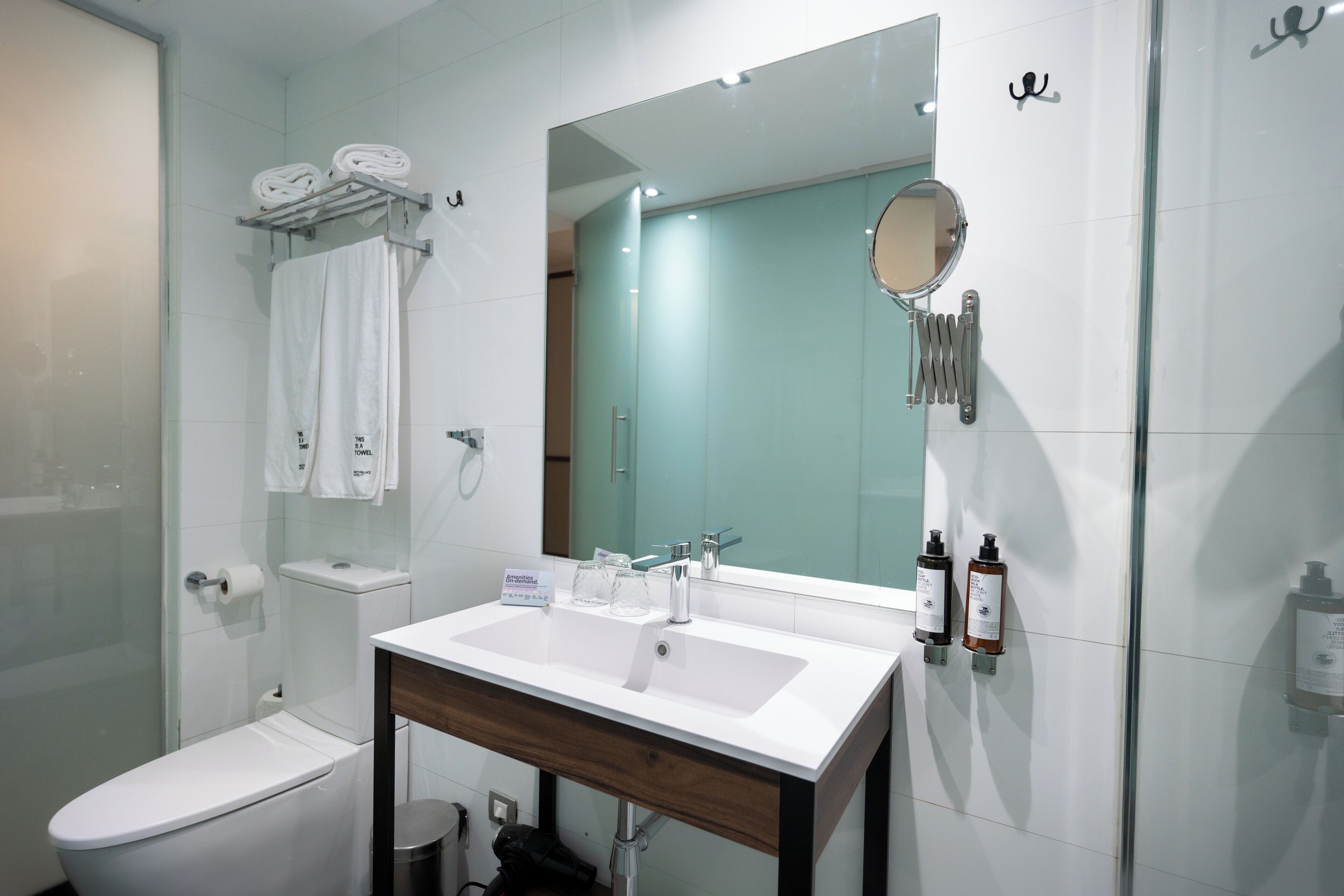 Un baño moderno con un lavamanos blanco, un espejo y un inodoro.