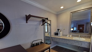Une salle de bain avec un comptoir en granit, un lavabo, un miroir, un banc et un four à micro-ondes.