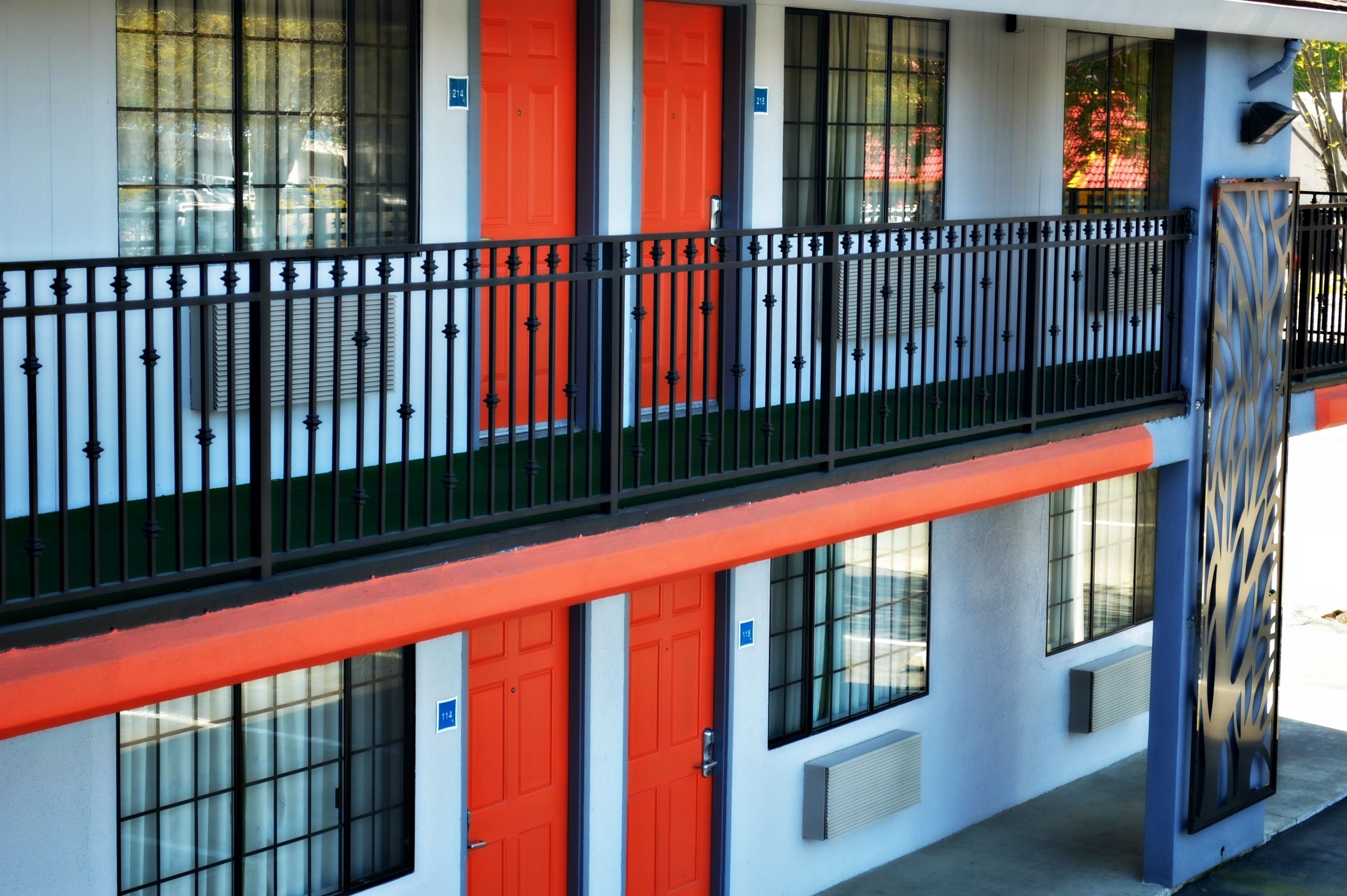 A building with a balcony, red doors, and a black railing.