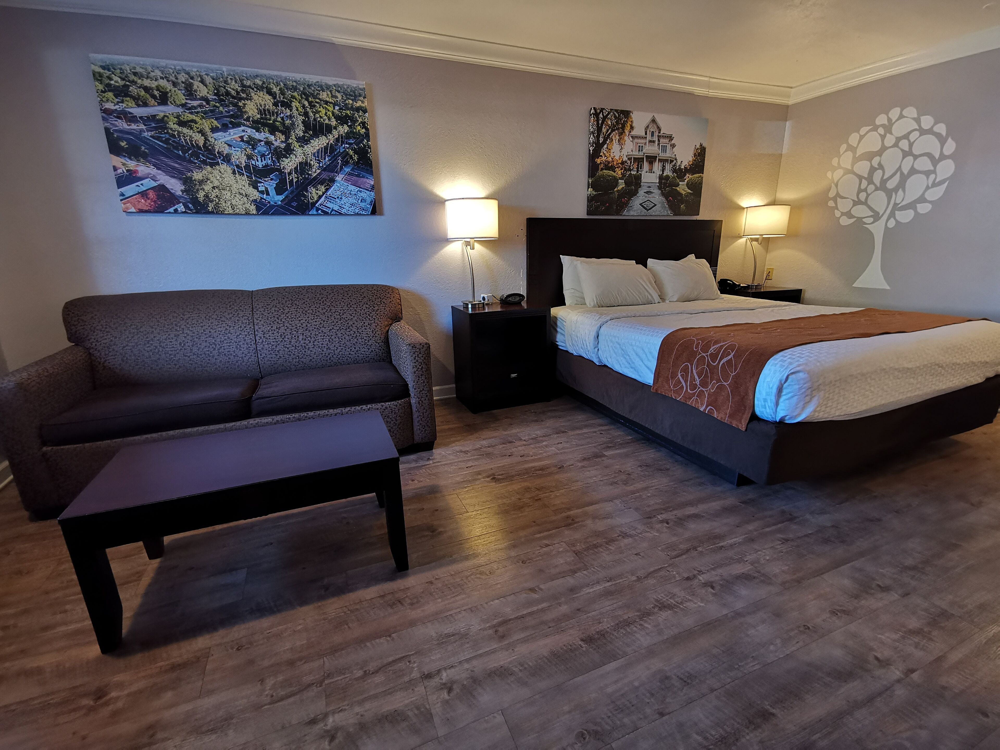 Een slaapkamer met een bed, een slaapbank, een nachtkastje en een wandlamp.