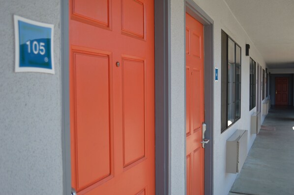 A corridor with orange doors, a number sign '105' on the wall, and a window on the right.