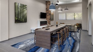 Una cocina moderna con una isla central, iluminación colgante y un amplio ventanal.