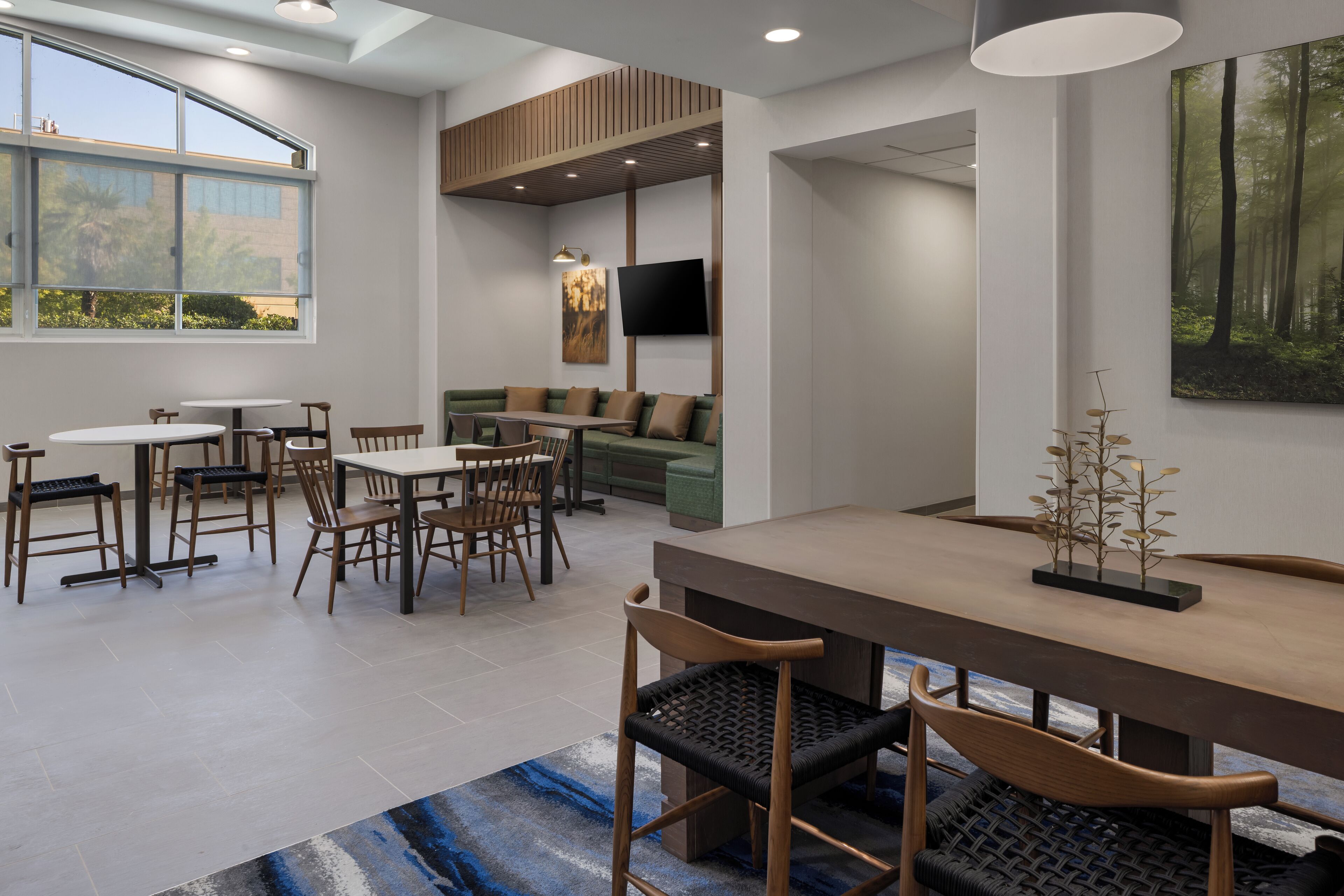 A modern dining area with a long table, multiple chairs, and a sofa.