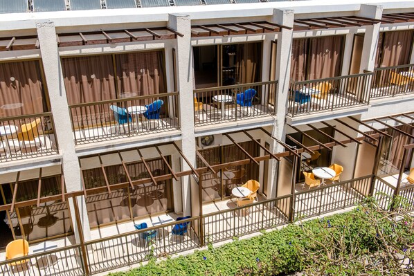 A multi-story hotel with balconies, outdoor seating, and a view of the surrounding area.