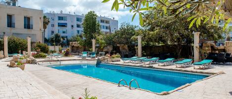 Una piscina al aire libre, sombrillas, sillones reclinables de piscina