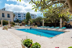 A swimming pool with lounge chairs and a stone patio.