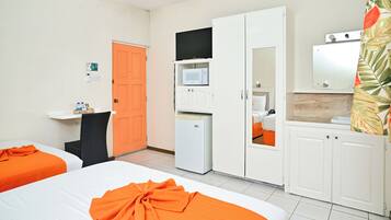A hotel room with two beds, a microwave, a refrigerator, a television, and a bathroom visible through an open door.