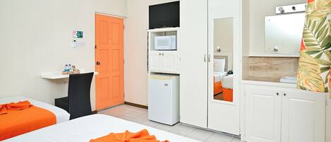A hotel room with two beds, a microwave, a refrigerator, a television, and a bathroom visible through an open door.