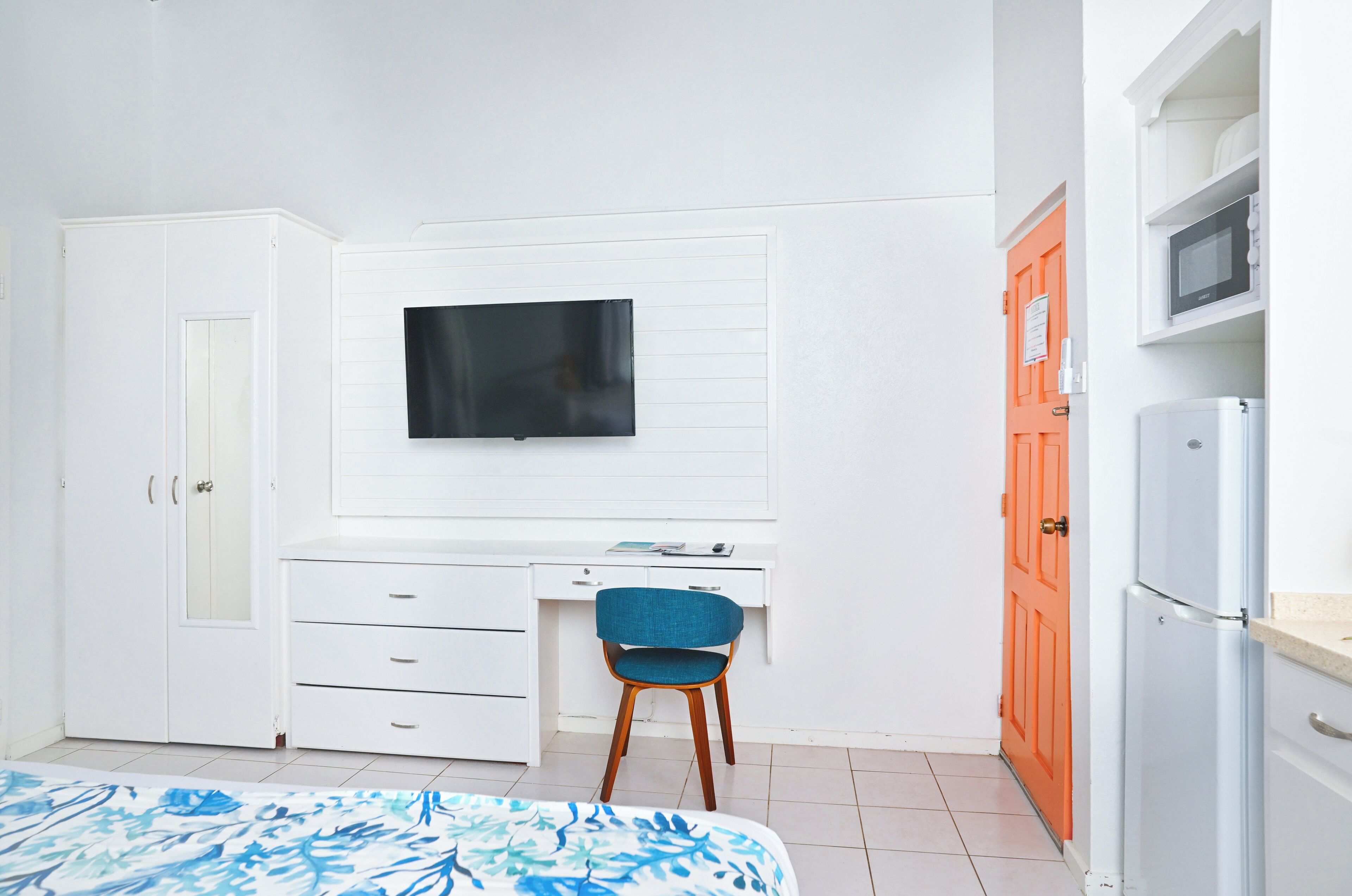 Une chambre à coucher comprenant un lit, un bureau, une chaise, un téléviseur et une armoire.