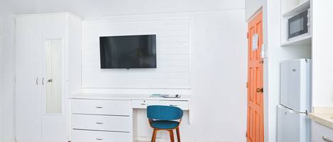 Une chambre à coucher comprenant un lit, un bureau, une chaise, un téléviseur et une armoire.