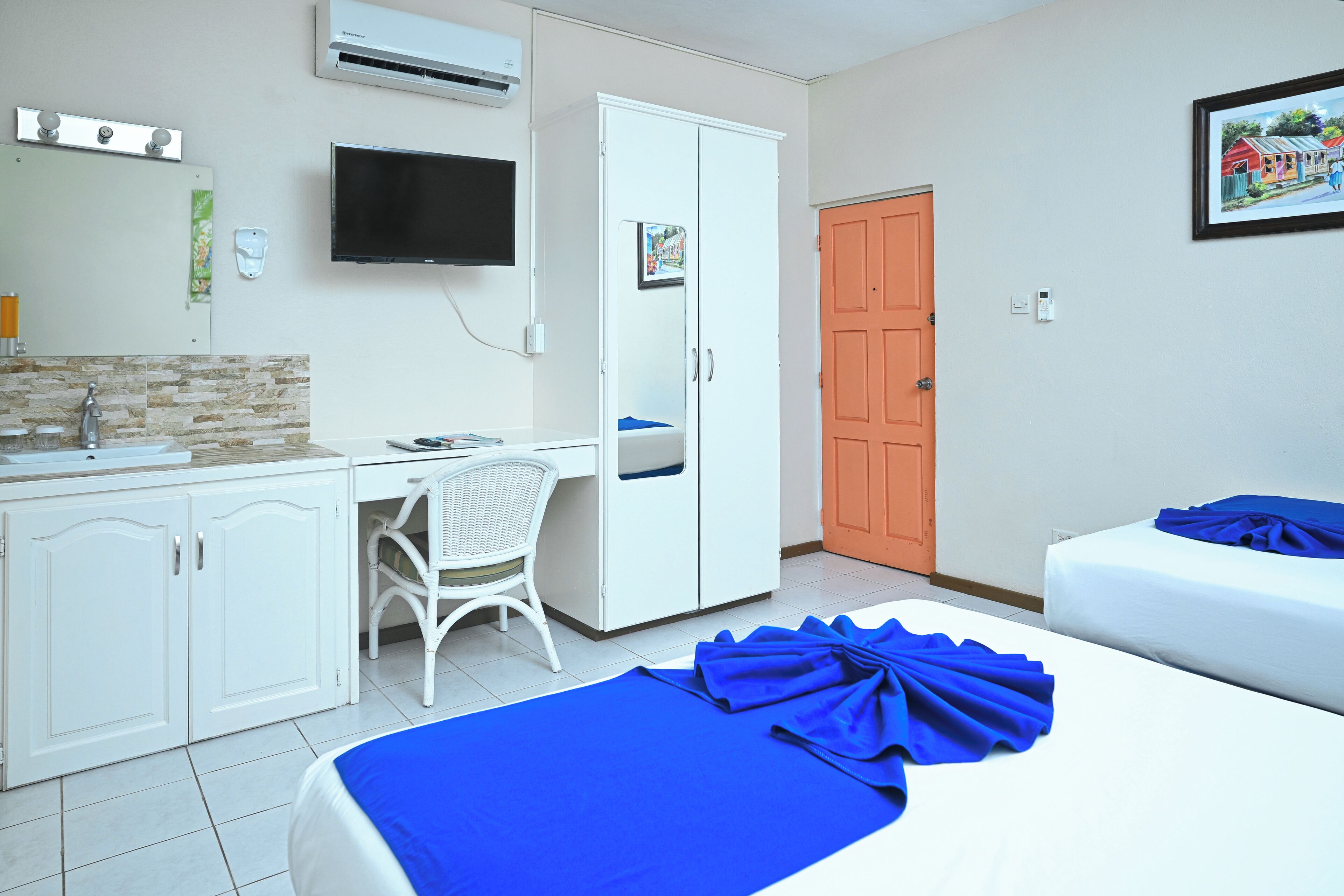 A hotel room with a bed, a desk, a chair, a wardrobe, and a television.