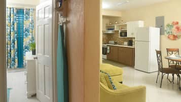 Una cocina con armarios blancos, un refrigerador y una mesa de comedor con sillas.