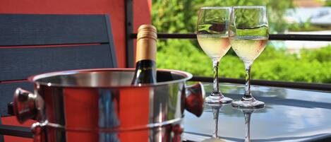 A metallic wine bucket with a bottle on a balcony table with two glasses of white wine.