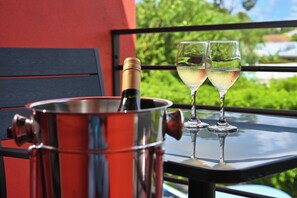 A metallic wine bucket with a bottle on a balcony table with two glasses of white wine. - Melbourne Inn (St. Lawrence Gap)