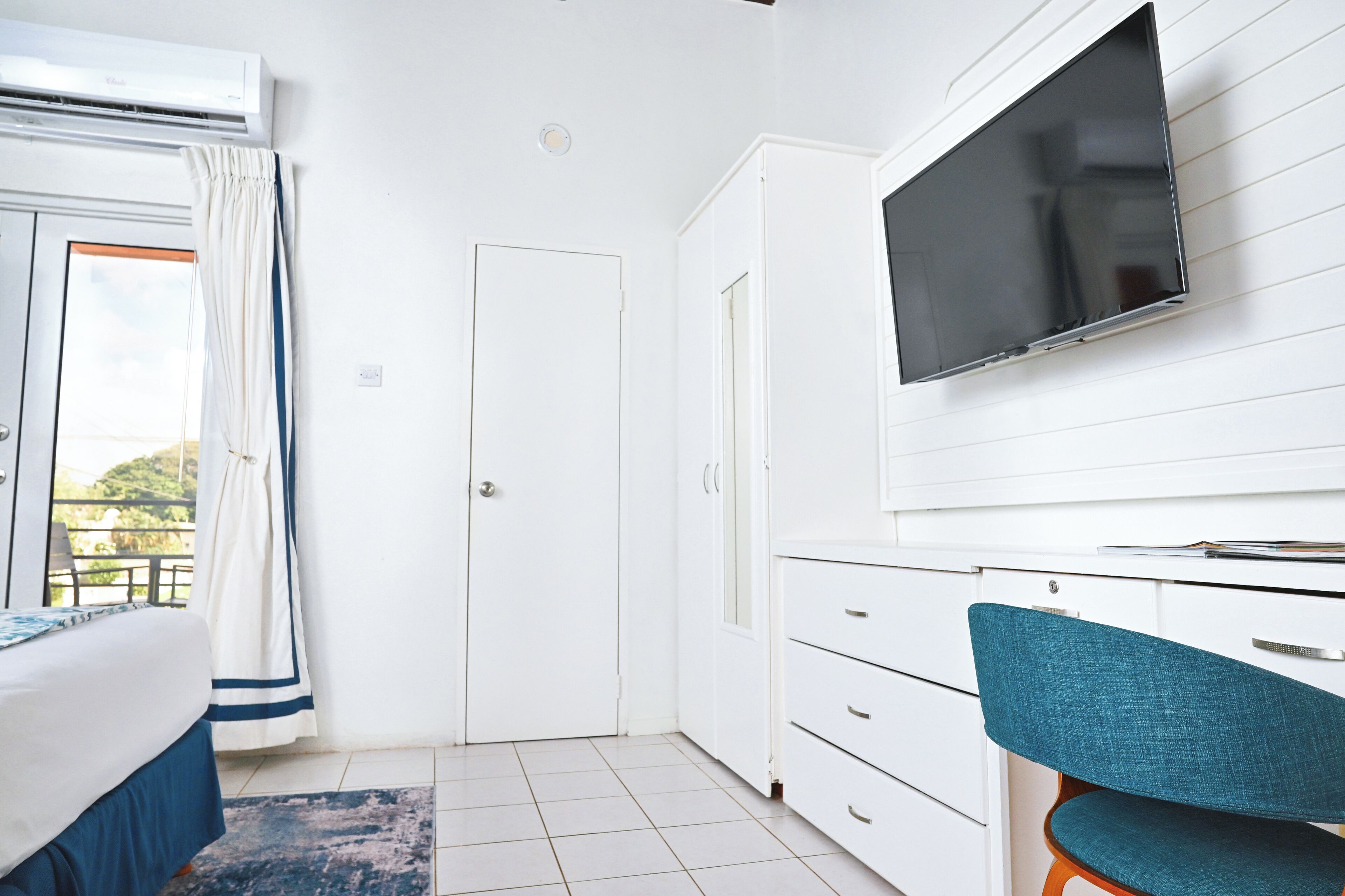 Un dormitorio con cama, escritorio, silla, televisor y armario.