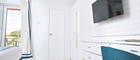 Un dormitorio con cama, escritorio, silla, televisor y armario.