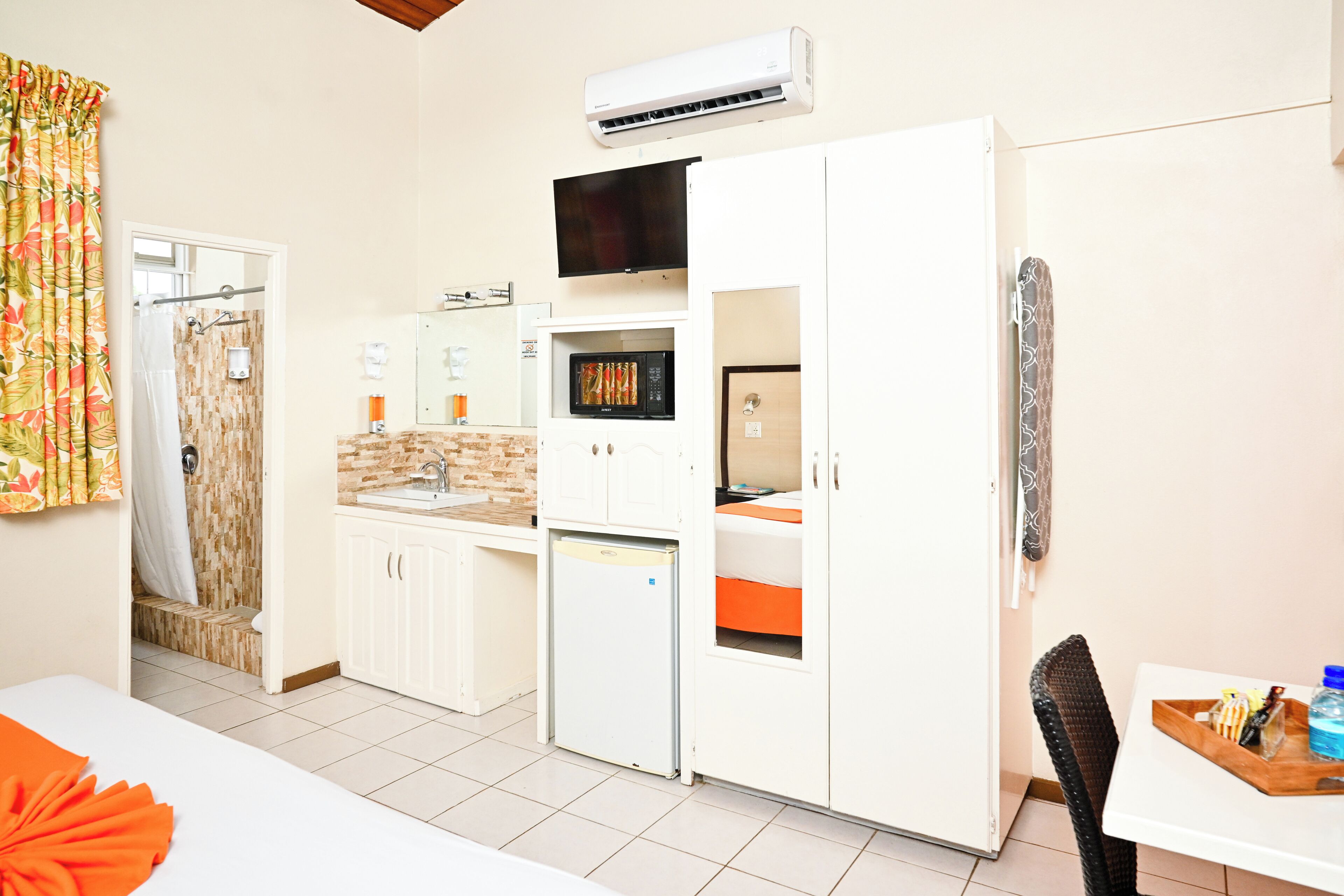 Una cocina compacta con microondas, refrigerador y un lavamanos pequeño.